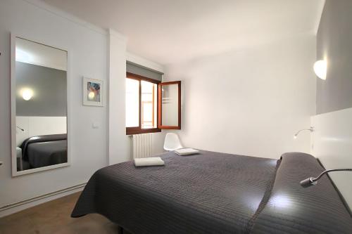 Schlafzimmer mit einem schwarzen Bett und einem Spiegel in der Unterkunft Cala Figuera Apartment 4b in Cala Figuera