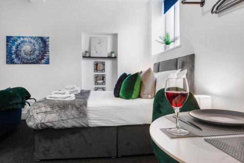 a bedroom with a bed and a table with a glass of wine at WhiskAwayStays Foregate Studio No 3 in Worcester