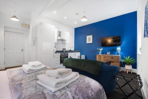 a living room with a couch and a blue wall at WhiskAwayStays Foregate Studio No 3 in Worcester
