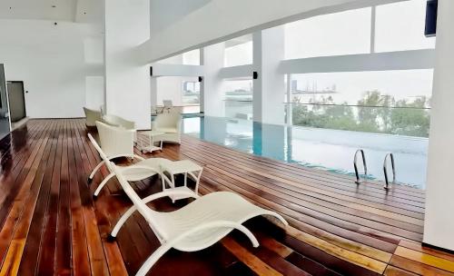 a living room with white chairs and a swimming pool at Sunrise @ Gurney in George Town