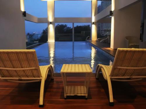 a room with two chairs and a table and a pool at Sunrise @ Gurney in George Town