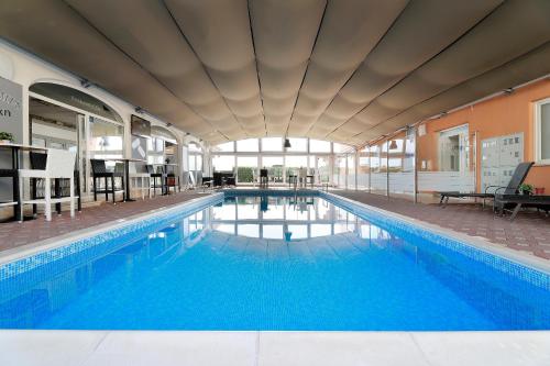 a large swimming pool with blue water in a building at Ratko Peris in Novalja