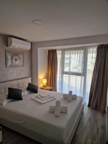 a bedroom with a large white bed with a window at Apartamente Topaz Sea View Olimp in Olimp