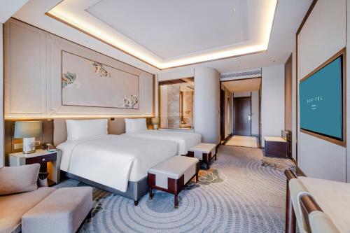 a hotel room with a large bed and a couch at Sofitel Xiong An in Baoding