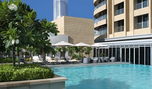 a swimming pool with chairs and umbrellas in front of a building at Paradise View The Dubai Mall Residences in Dubai