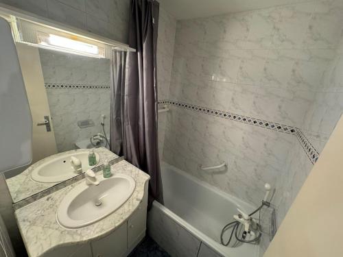 une salle de bain avec un lavabo et une baignoire dans l'établissement Appartement - Cap d'Agde, au Cap d'Agde