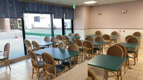 a dining room with green tables and chairs at 青森フォレストホテル アネックス in Aomori
