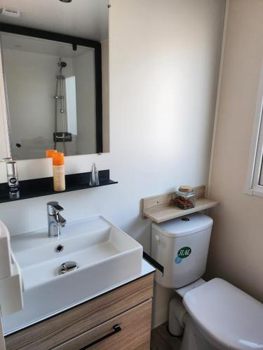 une salle de bain avec un lavabo, des toilettes et un miroir dans l'établissement Bungalow 410, 8 pers Camping 4 étoiles Siblu Le Lac des Rêves, à Lattes