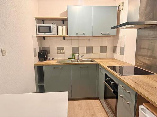 une cuisine avec un évier et un micro-ondes dans l'établissement Appartement Cosy à Belfort, à Belfort