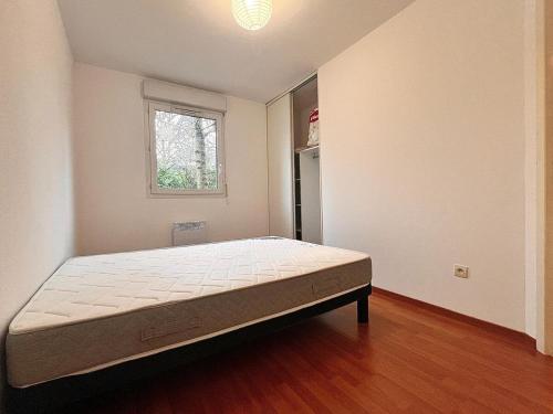 une chambre avec un lit dans une pièce avec une fenêtre dans l'établissement Appartement Cosy à Belfort, à Belfort