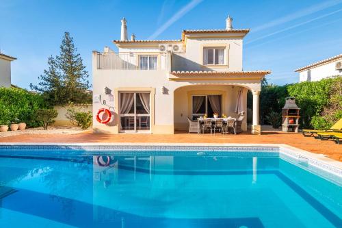 a villa with a swimming pool in front of a house at Villa Oasis, Piscina, Jacuzzi, Ténis e Praias! in Portimão