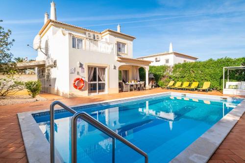 a villa with a swimming pool in front of a house at Villa Oasis, Piscina, Jacuzzi, Ténis e Praias! in Portimão
