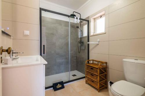 a bathroom with a shower and a toilet and a sink at Villa Oasis, Piscina, Jacuzzi, Ténis e Praias! in Portimão