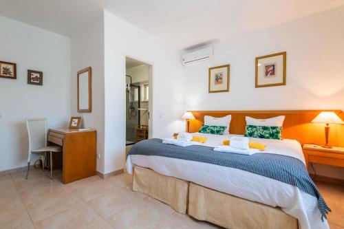 a bedroom with a large bed with a desk and a chair at Villa Oasis, Piscina, Jacuzzi, Ténis e Praias! in Portimão
