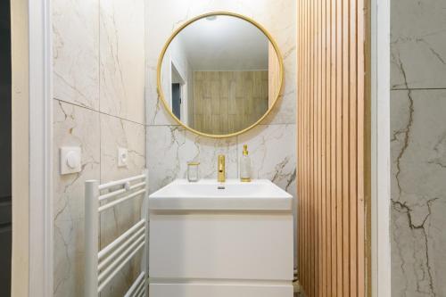 une salle de bain avec un lavabo et un miroir dans l'établissement Aux Berges de Bailly - A 10min de Disneyland, à Bailly-Romainvilliers