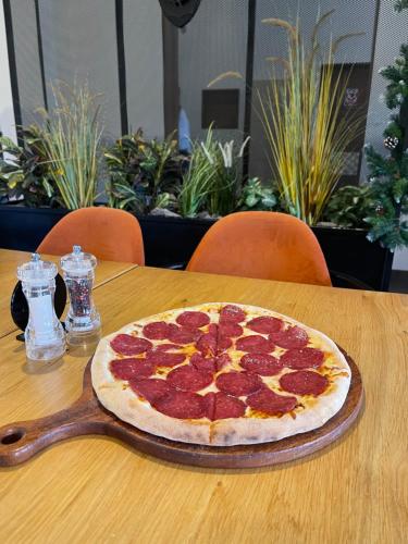 a pepperoni pizza sitting on top of a wooden table at Hotel Oscar in Campina