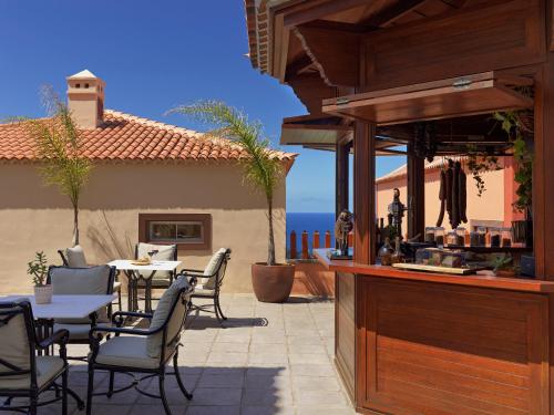 a patio with a table and chairs and a bar at Hotel Hacienda del Conde Meliá Collection Golf & Spa - Adults Only in Buenavista del Norte