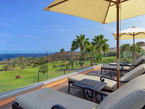 a patio with chairs and umbrellas on a deck with a view at Hotel Hacienda del Conde Meliá Collection Golf & Spa - Adults Only in Buenavista del Norte