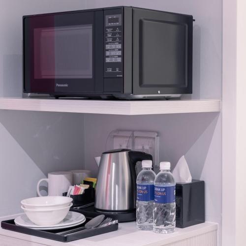 a microwave oven and two bottles of water on a shelf at Holiday Inn Express & Suites Johor Bahru by IHG in Johor Bahru