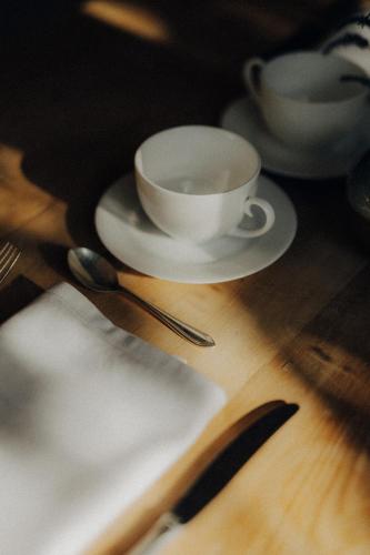 a table with two cups and a plate and spoon at Boutique-Hotel Ballguthof am Golfplatz in Lana