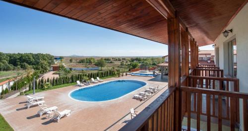 a balcony with a view of a swimming pool and chairs at Villa Trakia in Simeonovo