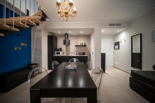 a dining room and kitchen with a black table and chairs at Napoleon Suites & Apartments in Susa
