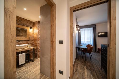a room with a bathroom with a sink and a table at Napoleon Suites & Apartments in Susa