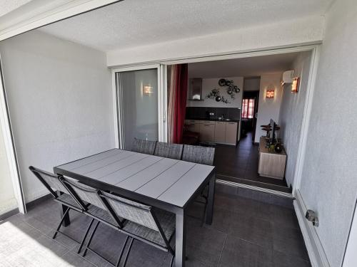 une salle à manger avec une table et des chaises et une cuisine dans l'établissement Appartement POMME D'AMOUR Port Nature PN423 - Luxe - 2 personnes, au Cap d'Agde