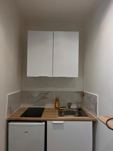 - une cuisine avec un évier et des placards blancs dans l'établissement joli petit studio, à Mantes-la-Jolie