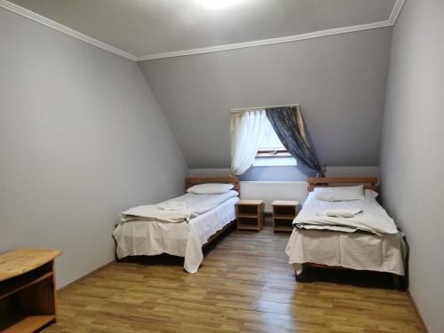 two beds in a small room with a window at Хостел-готель Кремзлик in Yasinya
