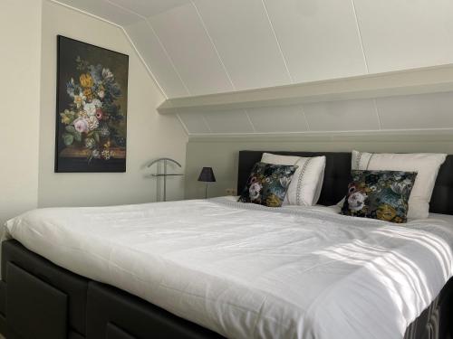 a bedroom with a large white bed with pillows at Holiday home Zwanesteijn in Heerde