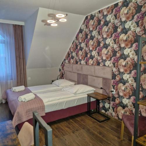 a bedroom with a bed with a floral wall at Jarzębinowy Resort & SPA in Braniewo