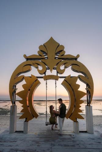 a couple sitting on a swing at the beach at Ombak Sunset in Gili Trawangan