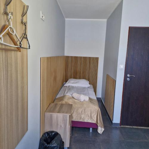 a small bedroom with a bed with a wooden headboard at Jarzębinowy Resort & SPA in Braniewo