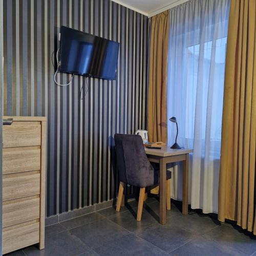 a desk with a chair and a television on a wall at Jarzębinowy Resort & SPA in Braniewo