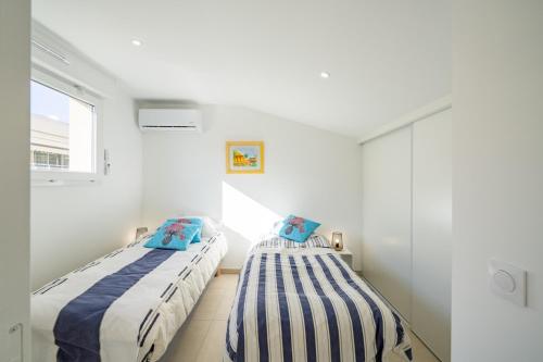 Ce lit se trouve dans un dortoir doté de murs blancs et d'une fenêtre. dans l'établissement Les Voiles d Azur, Duplex moderne avec vue sur le port et la mer, à 2 minutes des plages, à Vallauris