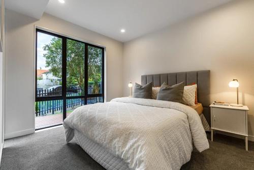 a bedroom with a large bed and a large window at Mission Bay 4 bedrooms Tidy Unit in Auckland