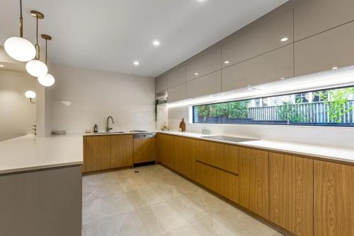 a large kitchen with wooden cabinets and a window at Mission Bay 4 bedrooms Tidy Unit in Auckland