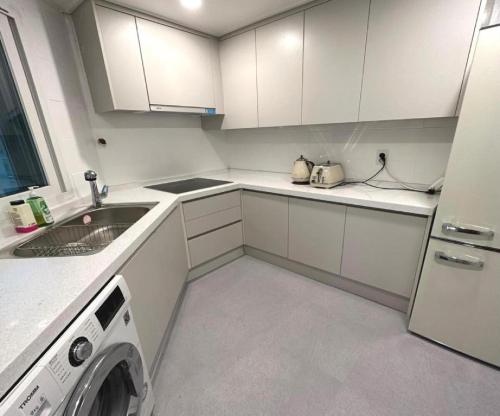 a white kitchen with a sink and a washing machine at New Jins House - 5mins to Myeongdong station, 3 rooms, big living rooms in Seoul