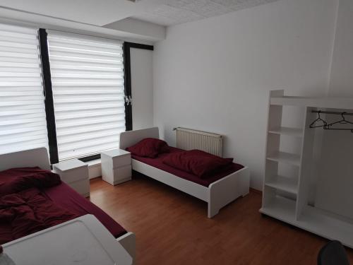 a bedroom with two beds and a window with blinds at MonteurGut Apartments Eiche in Lindern