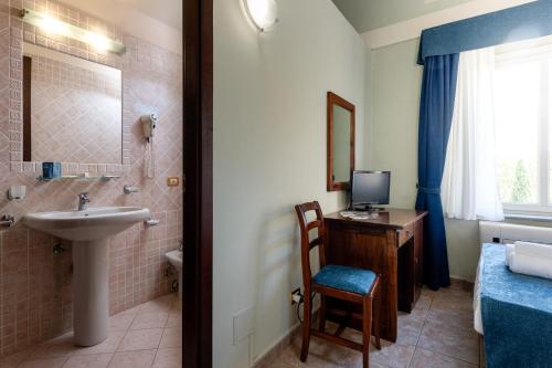 a bathroom with a sink and a desk with a television at Borgo San Martino - Residence Hotel & SPA in Riparbella