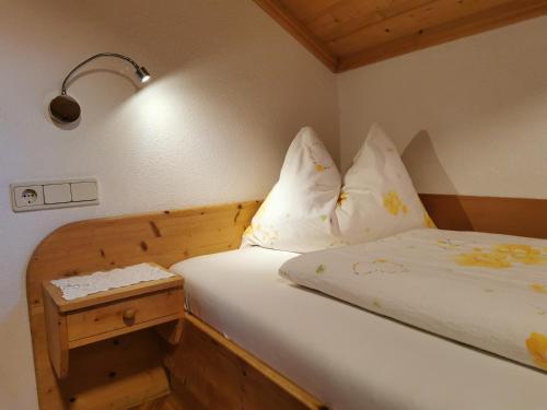 a small bedroom with a bed and a night stand at Moosbachhof - Ferienwohnung Marienkäfer in Collalbo