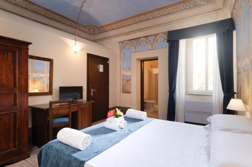a bedroom with a bed and a desk with flowers on it at Borgo San Martino - Residence Hotel & SPA in Riparbella