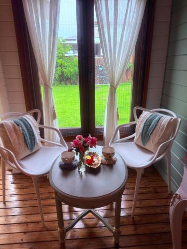 a room with two chairs and a table with flowers on it at Blissful Wooden Haven - complete place is yours 5 min drive or train from parramatta in Wentworthville