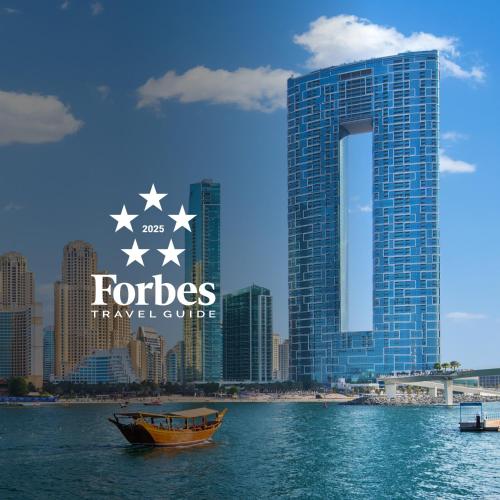 a boat in the water in front of a tall building at Address Beach Resort in Dubai