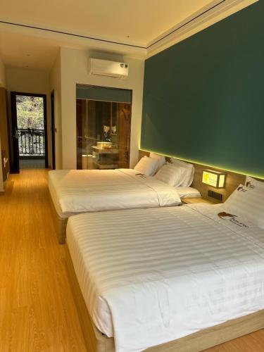 two beds in a hotel room with a green wall at Tam Coc Wonderland Lodge in Ninh Binh