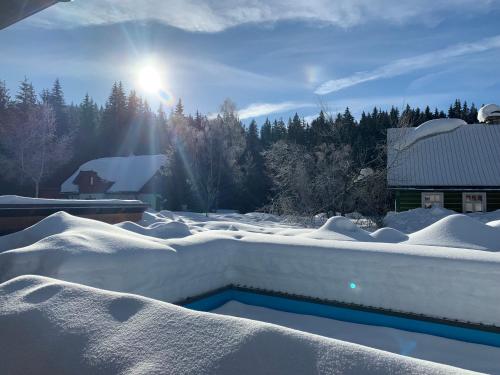 a swimming pool covered in snow next to a barn at Chalet Schäfer s vyhřívaným bazénem se slanou vodou in Harrachov