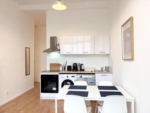 une cuisine avec une table et des chaises ainsi qu'un lave-linge. dans l'établissement Appartement 6 voyageurs - Roubaix, à Roubaix
