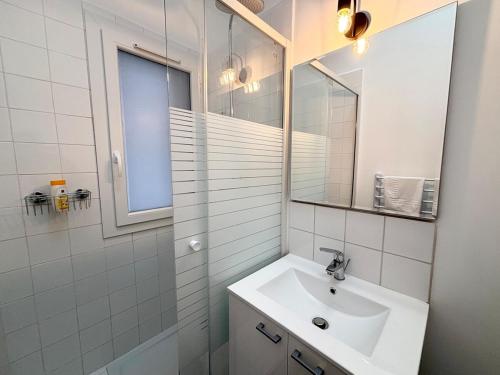 une salle de bain blanche avec un lavabo et un miroir dans l'établissement Appartement 6 voyageurs - Roubaix, à Roubaix