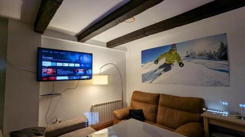 a living room with a couch and a flat screen tv at Apartamento Nievesol con 2 Parking y WiFi in Sierra Nevada
